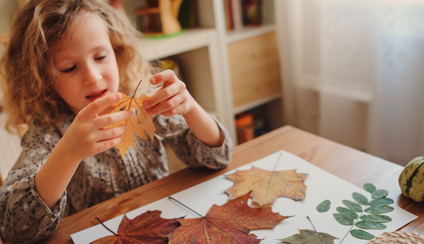 children playing with autumn leaves at table